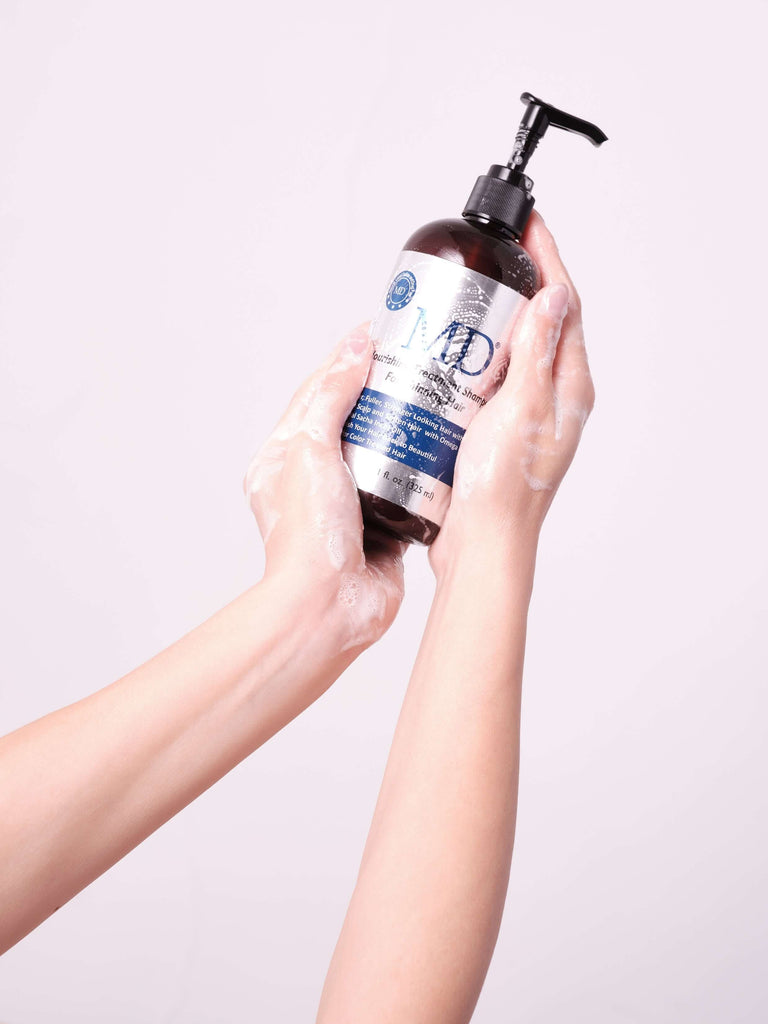 Hand holding MD® Revitalizing Treatment Shampoo bottle – sulfate-free DHT-blocking formula for thinning hair and scalp health, from the MD Hair system